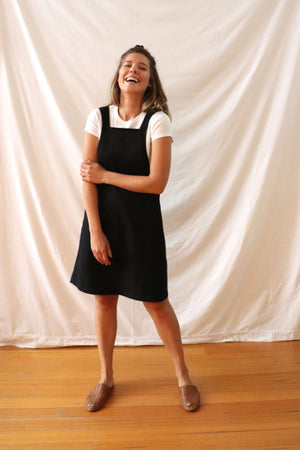 Ethically made pinafore style dress in black linen with one pocket. Mid length and short.